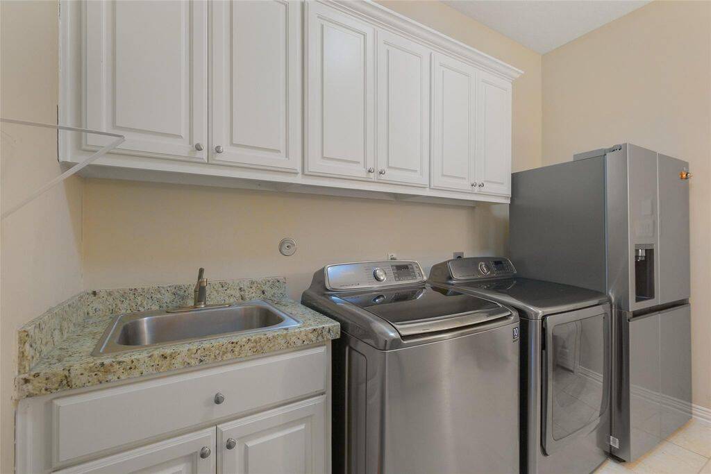 This huge laundry room is designed for both efficiency and convenience, offering everything you need to keep your home organized. Ample white cabinetry provides generous storage for cleaning supplies, linens, and household essentials, keeping everything neatly tucked away. With plenty of space to move around, this versatile room can also double as a mudroom, making it a practical addition for busy households.A laundry room that works as hard as you do—functional, stylish, and spacious!