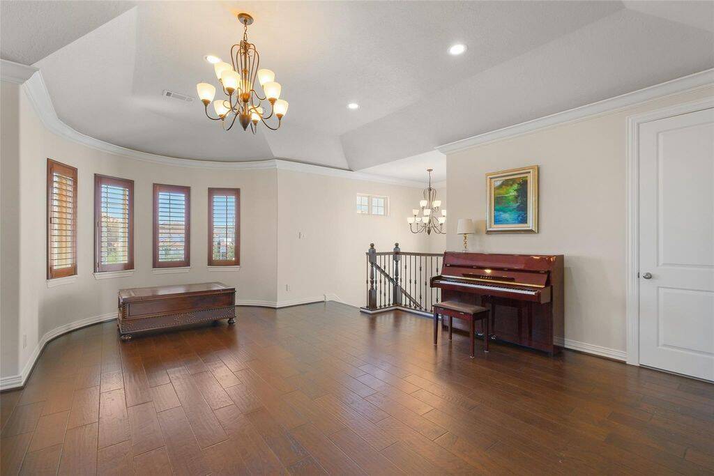 This beautifully designed upstairs loft offers a spacious and versatile area, perfect for a second living space, game room, or media retreat. Featuring rich hardwood floors, elegant tray ceilings, and soft recessed lighting, the room exudes warmth and sophistication.