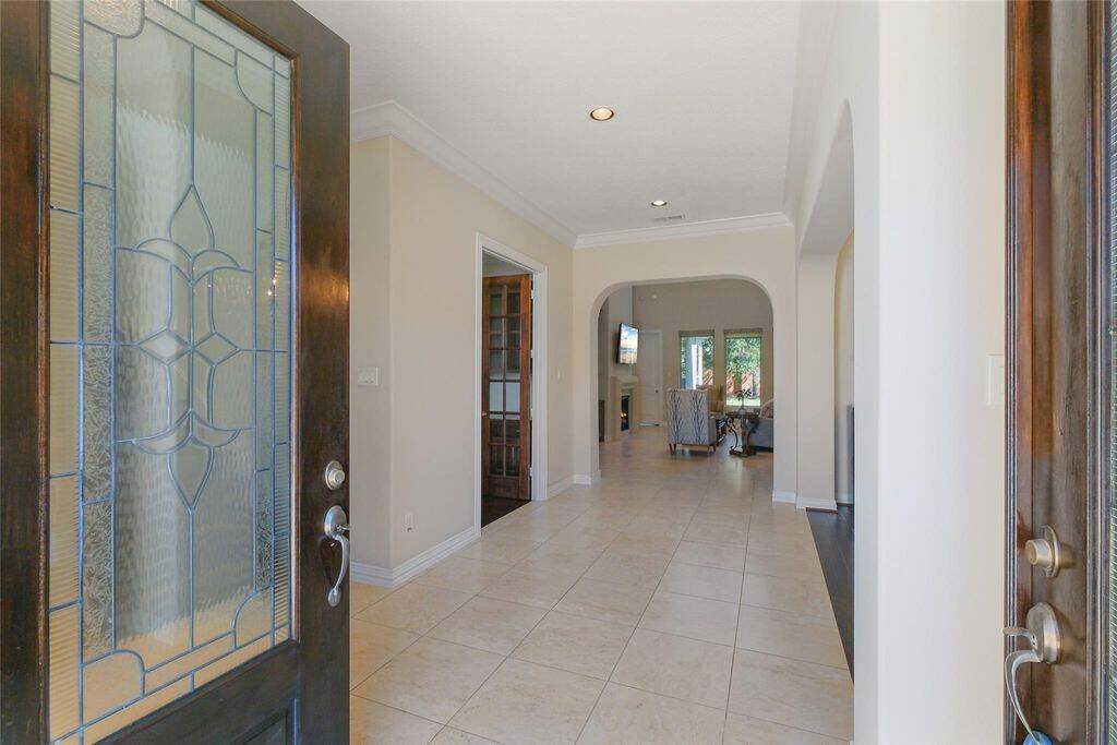 Step into a home that welcomes you with warmth and sophistication. The grand double doors with intricate glass detailing open to a bright and airy foyer. The open-concept layout features graceful archways, high ceilings, and stunning tile flooring that enhances the sense of space and luxury.