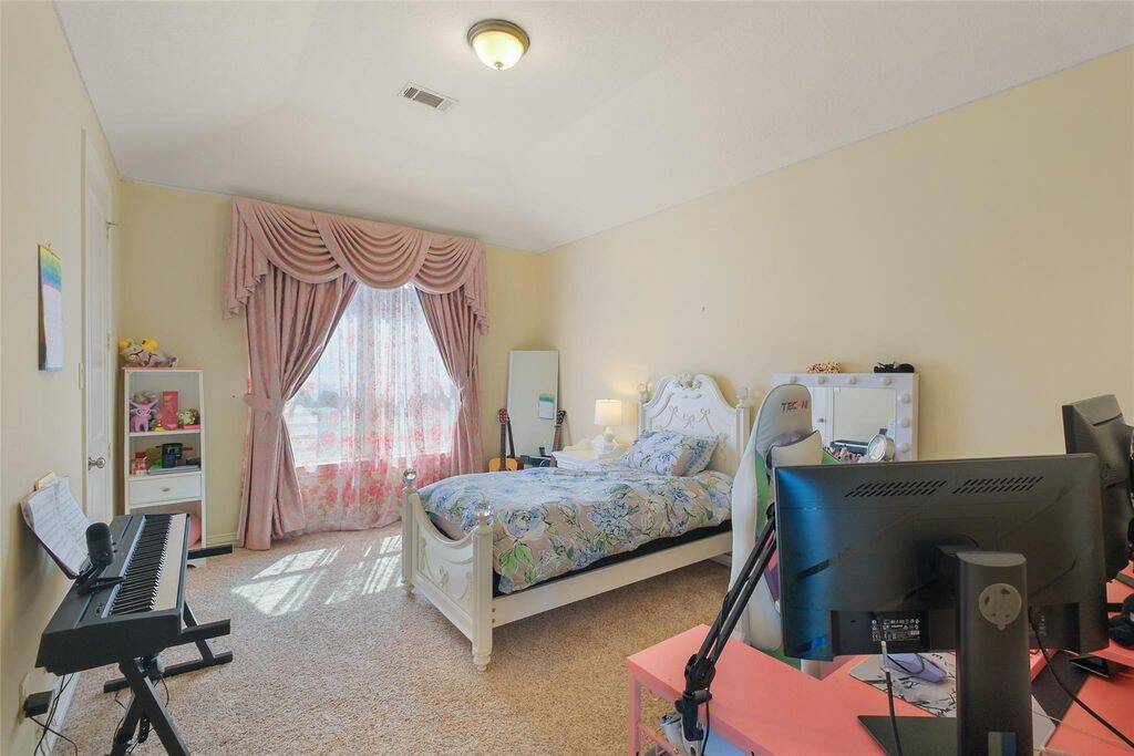 This inviting bedroom offers a warm and relaxing atmosphere, featuring plush carpeting, soft yellow walls, and a large window adorned with elegant drapes that allow natural light to fill the space.Designed for both comfort and practicality, this room boasts a generous closet, providing plenty of storage for clothing and essentials. The neutral color palette creates a versatile space, perfect for personalizing to suit any style.A bright and cozy retreat—ideal for restful nights and refreshing morning