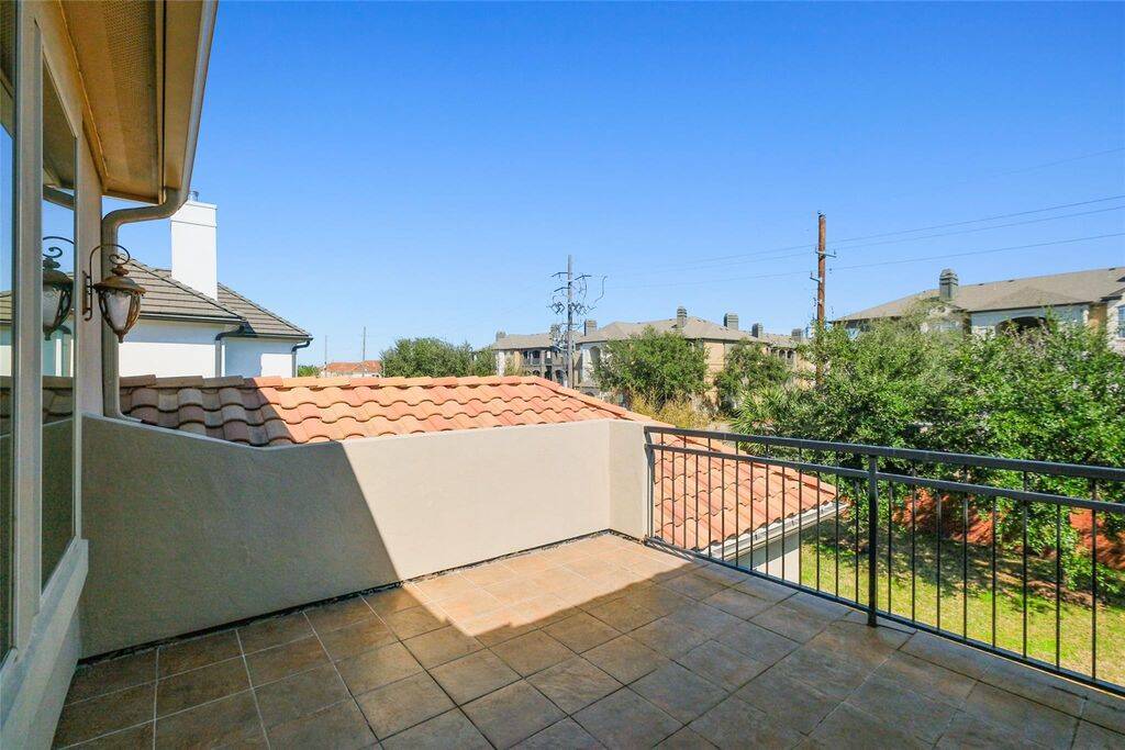 Step out onto this charming private balcony, the perfect retreat for enjoying fresh air and tranquil views. Featuring elegant tile flooring and a classic wrought iron railing, this outdoor space is ideal for morning coffee, evening relaxation, or simply soaking in the serene surroundings. With beautiful rooftop and greenery views, this balcony provides a peaceful escape while remaining connected to the home’s luxurious design. Use as a reading nook, meditation space, or a cozy spot to unwind!