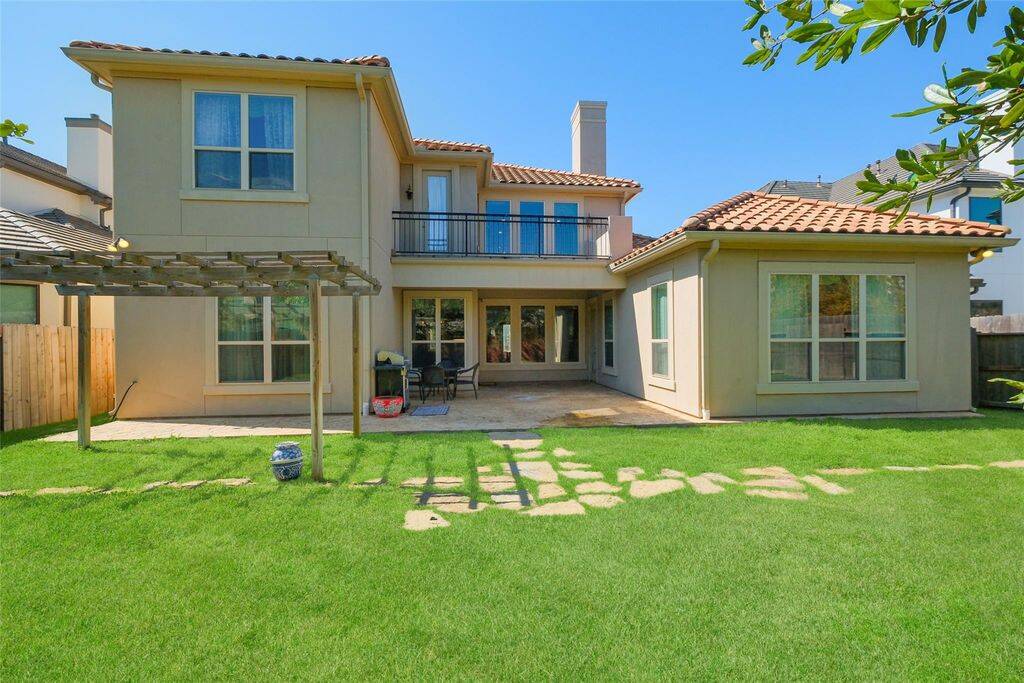 Experience seamless indoor-outdoor living in this beautifully designed backyard retreat. The lush green lawn, charming stone pathway, and wooden pergola create a tranquil setting perfect for relaxing or entertaining.