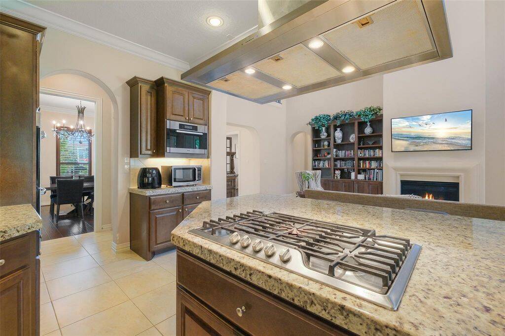 The stainless steel appliances, including a built-in double oven and a premium gas cooktop with a striking stainless steel vent hood, provide both luxury and efficiency.