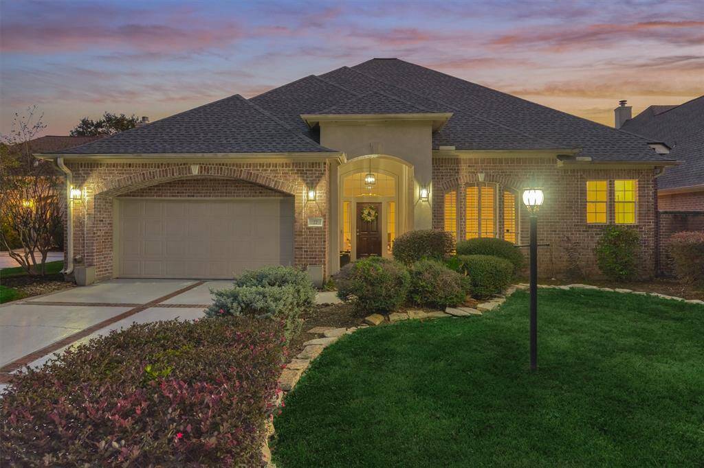 Arrive to striking curb appeal featuring a brick-lined driveway and lush foliage.