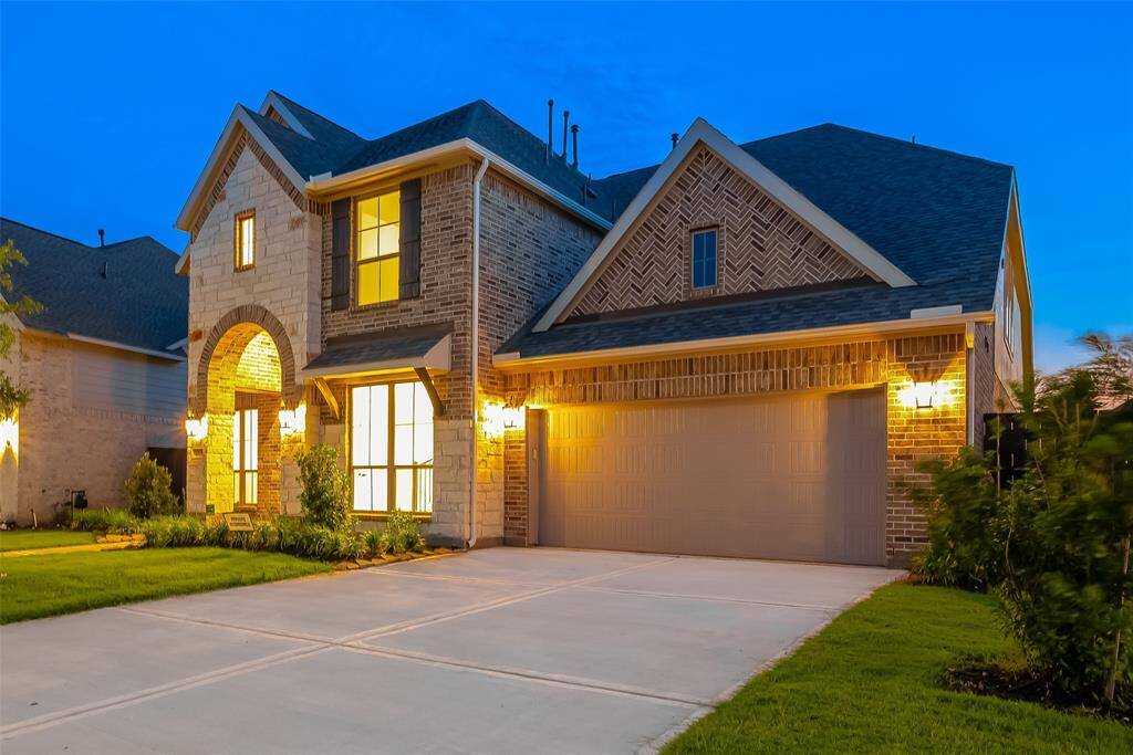 As you approach, you're greeted by a grand two-story porch entry adorned with striking glass and wood double doors, promising a warm welcome every time you enter.