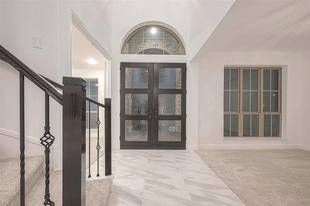 A dramatic two-story foyer with a soaring 21-foot ceiling sets the stage for the home's luxurious interior. A rotunda ceiling accents the curved wrought iron staircase, adding a touch of grandeur to the space.
