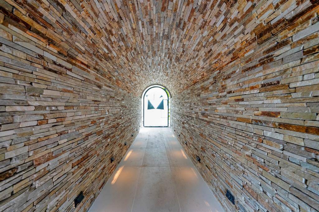 The medieval-looking vaulted passageway from the front yard to the back yard is clad with Virginia granite and provides a separate entry to the backyard pool area, bath tower and upstairs to the dance deck/media room.