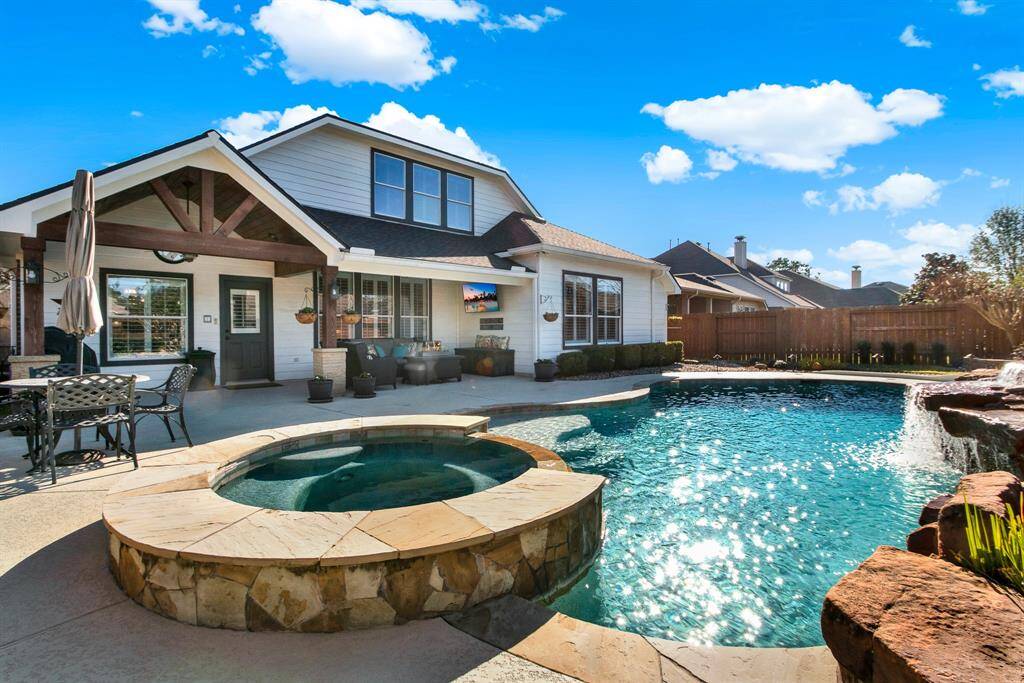 The patio area offers ample space for outdoor dining and lounging, enhanced by a charming waterfall feature and well-maintained landscaping.