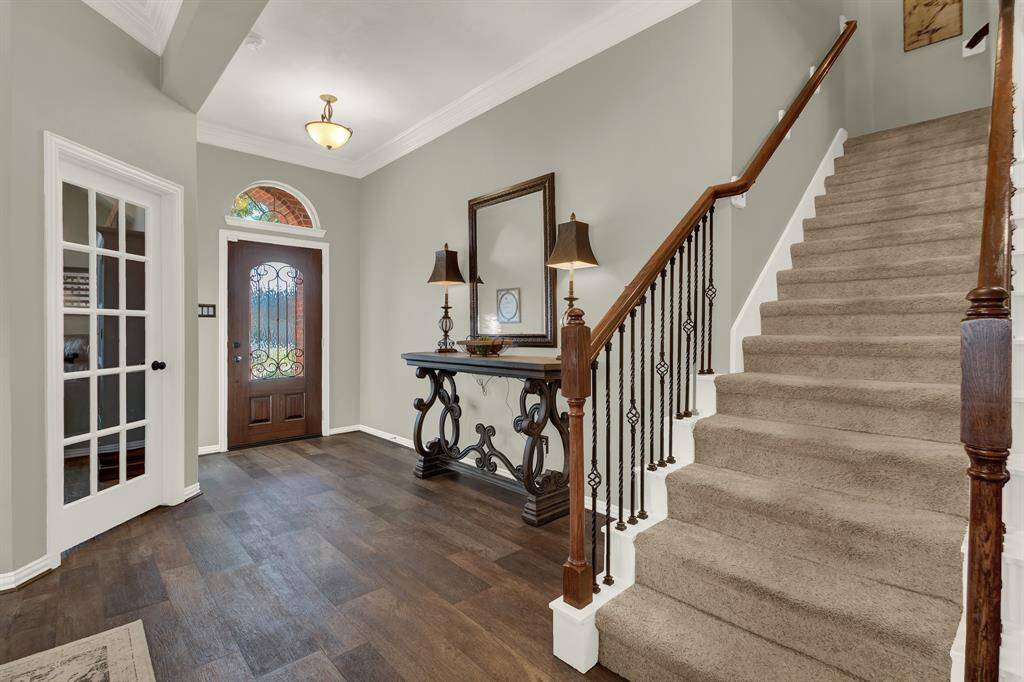 The entryway features a stylish front door with decorative glass and a carpeted staircase with a wrought iron railing.