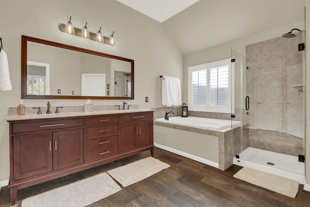 The primary bathroom features a double vanity with a large mirror, a glass-enclosed shower, and a separate soaking tub.