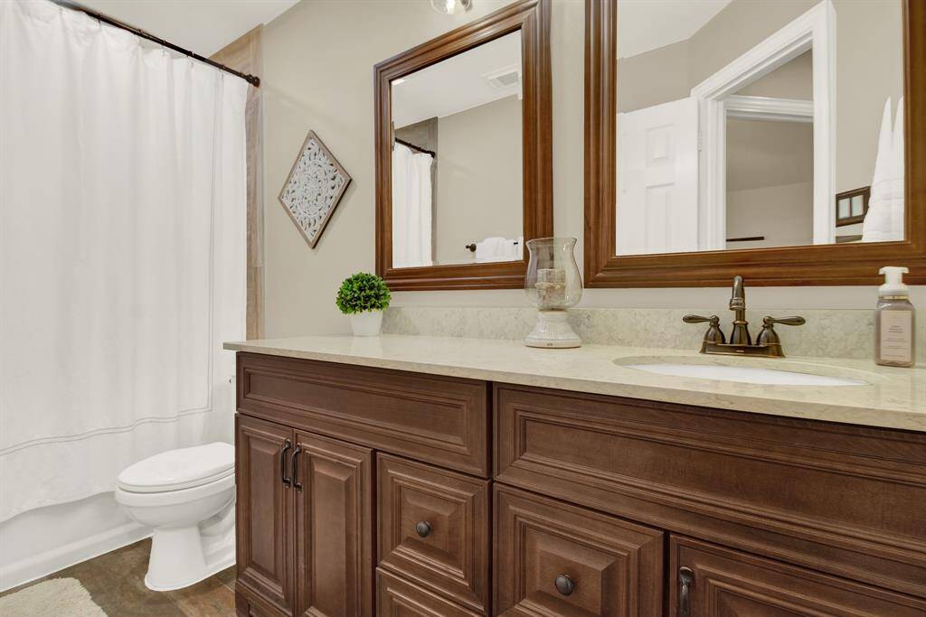 This bathroom features a classic design with a rich wood vanity, dual mirrors, and an elegant countertop.