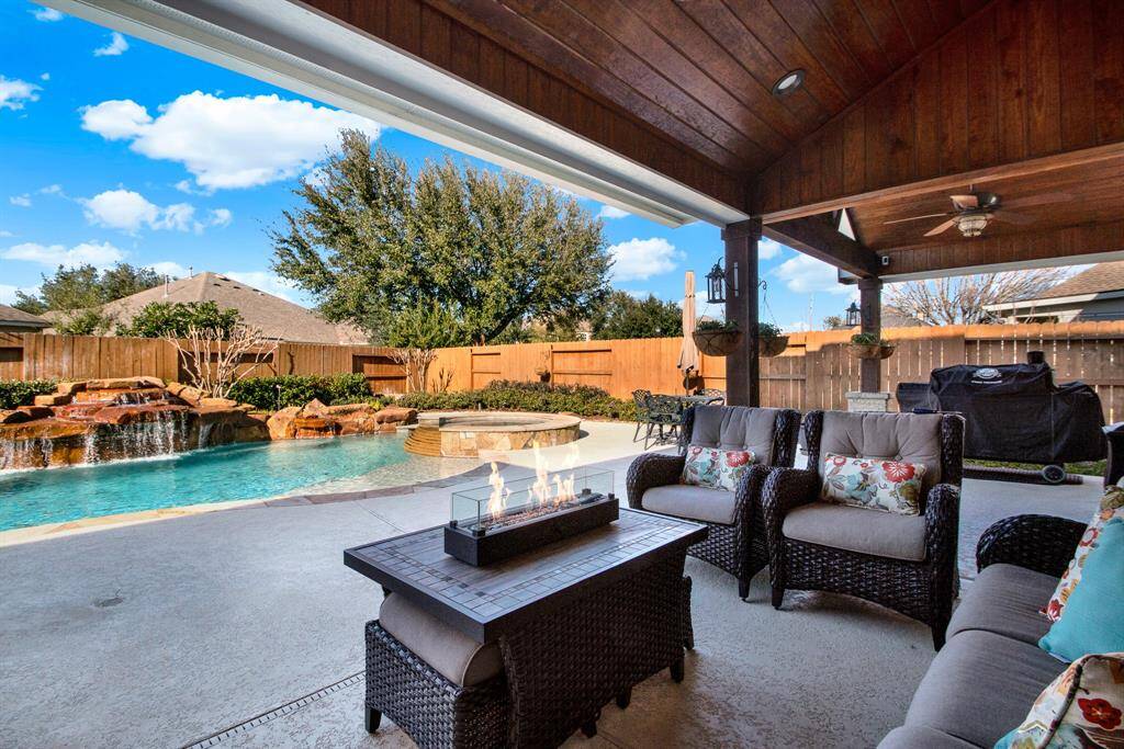 This outdoor space features a covered patio with comfortable seating and a fire table.