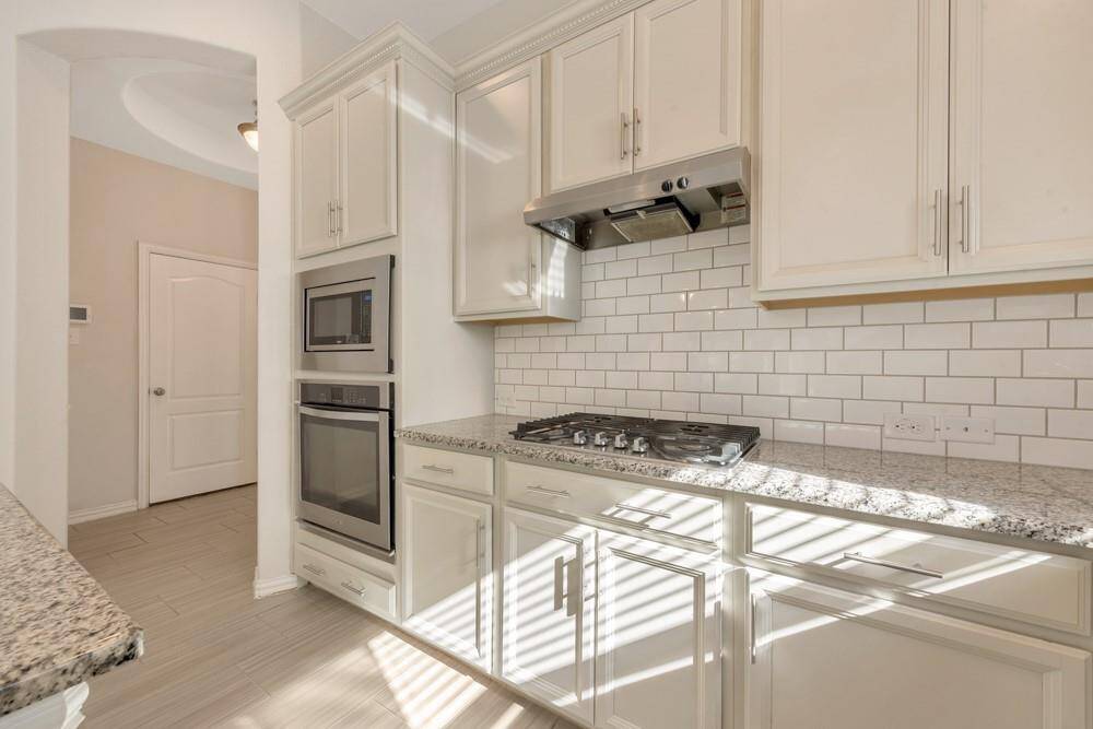 Modern kitchen with sleek stainless steel appliances, white cabinetry, and a stylish subway tile backsplash. The granite countertops add elegance, and the space is well-lit with natural light.