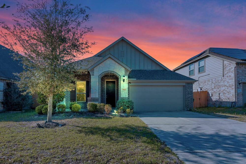 This charming single-story home features a modern brick and stone facade, a welcoming arched entryway, and a two-car garage. The front yard is landscaped with neatly trimmed shrubs and a well-maintained lawn, enhancing its curb appeal.