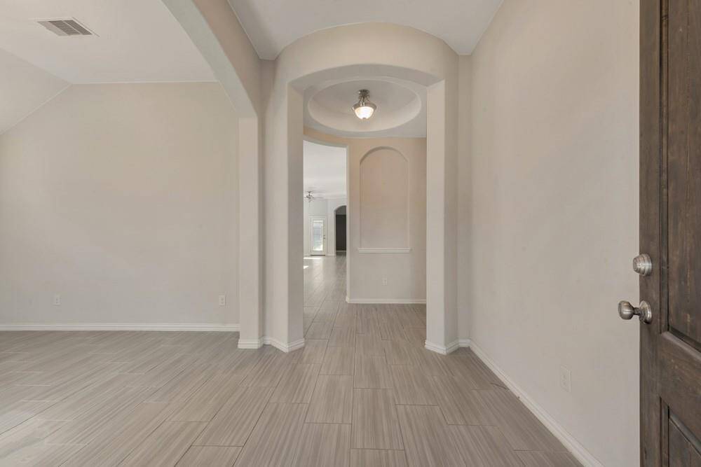 Bright entryway with elegant archways and neutral, modern tile flooring, leading to spacious, open living areas.