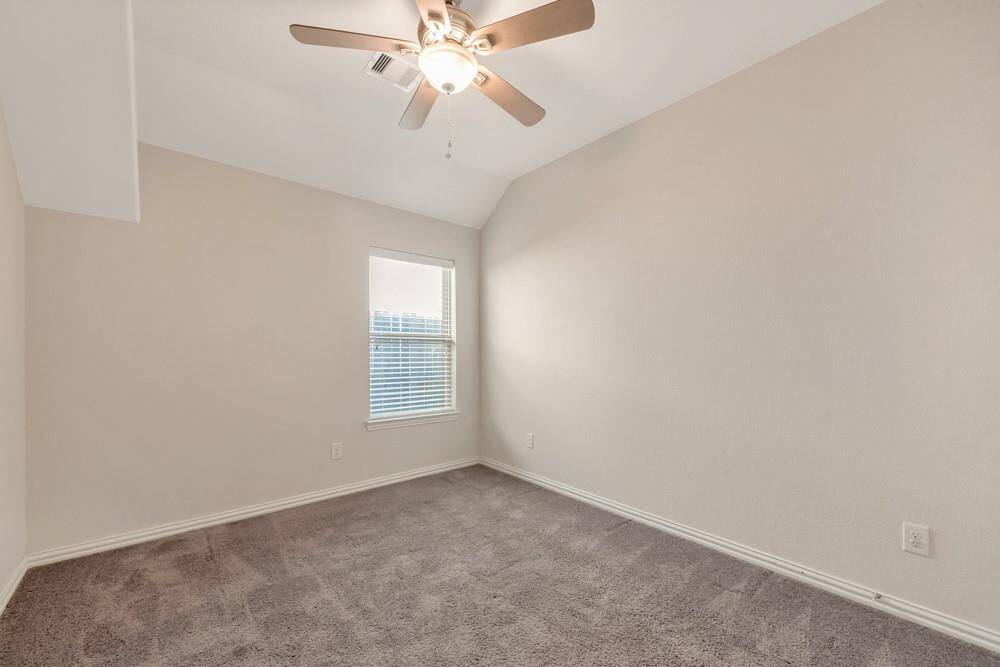 This room features neutral walls, a plush carpet, a ceiling fan, and a window providing natural light. Perfect for a cozy bedroom or office space.