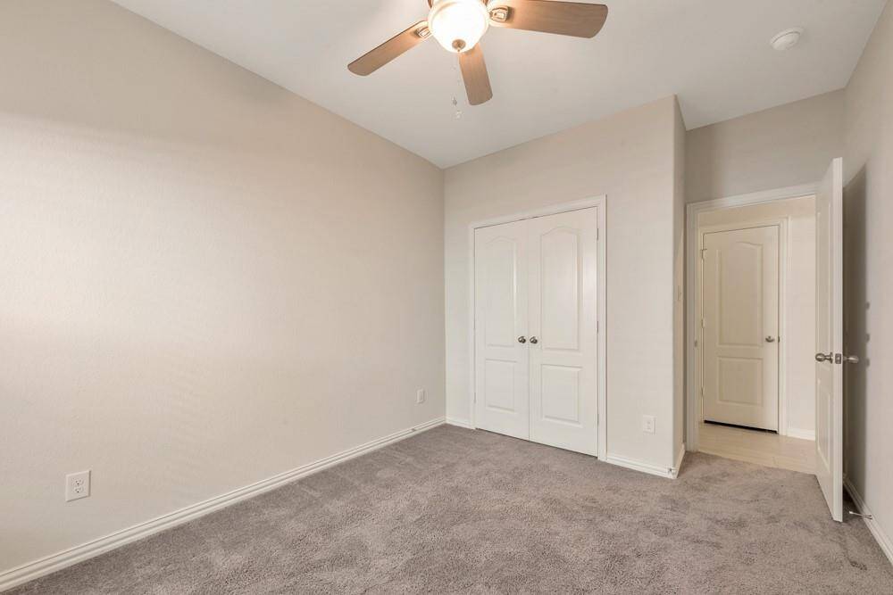 This is a bright, cozy bedroom with neutral walls, carpeted flooring, a ceiling fan, and a double-door closet. Perfect as a guest room or office space.