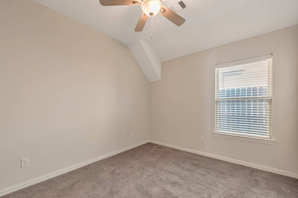 This is a small, cozy room with neutral walls and carpeted flooring, featuring a ceiling fan and a window that provides natural light. Ideal for use as a guest room or office space.