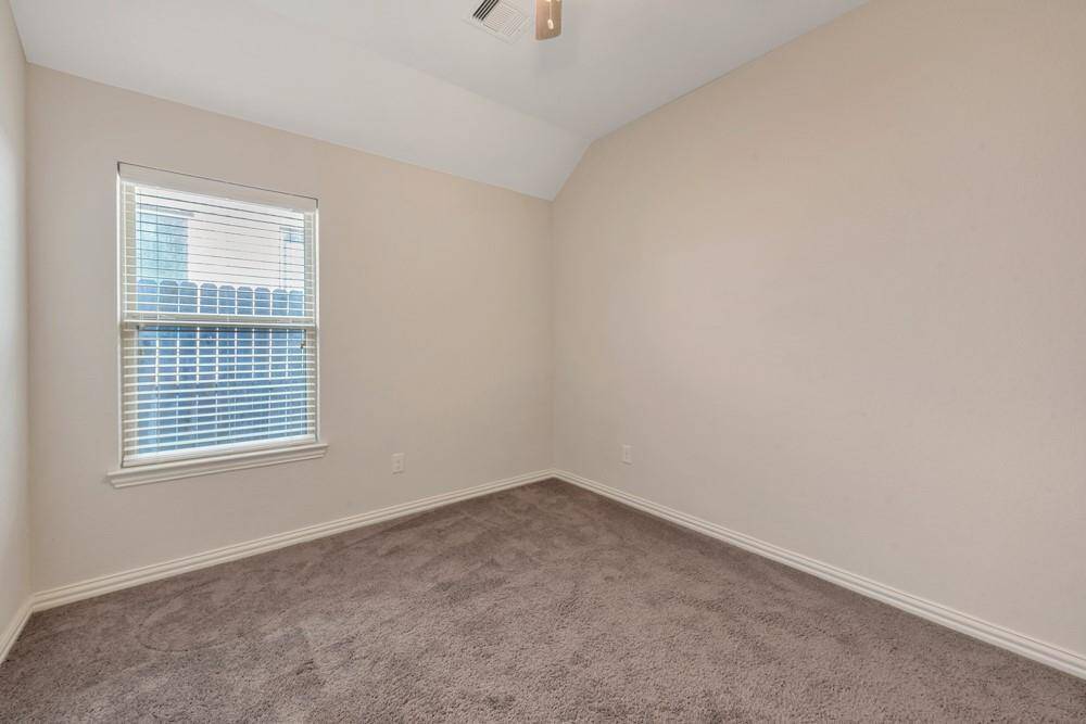 This photo shows a small, carpeted bedroom with neutral walls, a window with blinds, and a ceiling vent. It has a cozy, clean appearance, ideal for a guest room or office space.