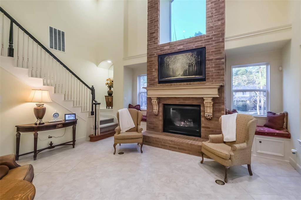 The living room is centered around one of the three fireplaces in the home and features a beautiful mantle, bench seating, durable tile flooring and in-floor electrical outlets for task lighting. Notice the framed television which stays with the house!