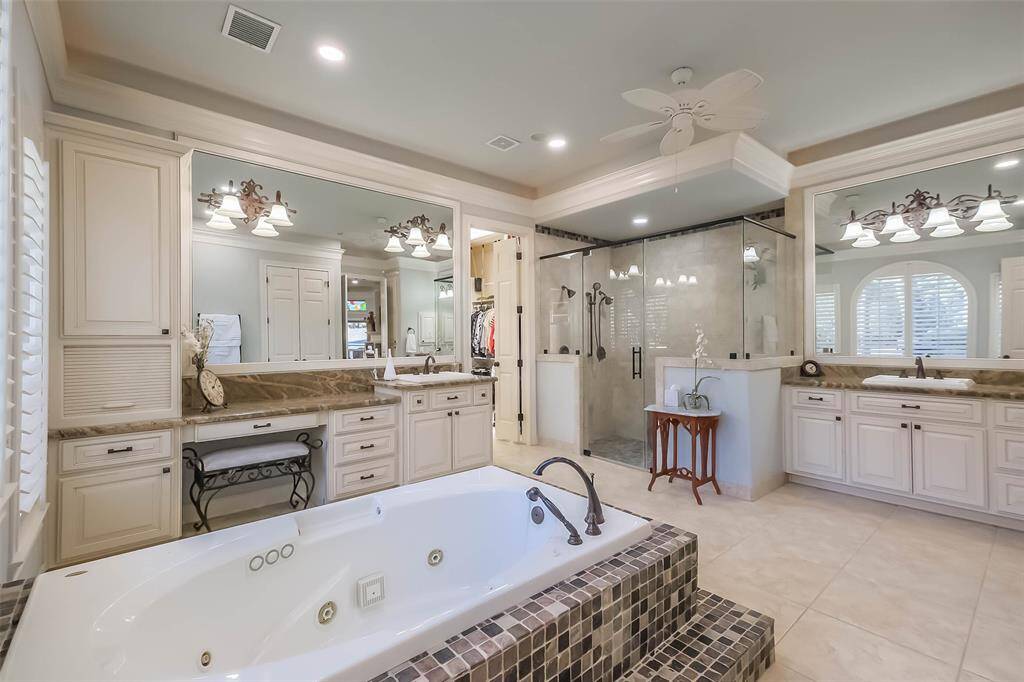 The spacious primary bath features a jetted tub, large walk in frameless glass shower, dual vanities with vanity area and plenty of storage.