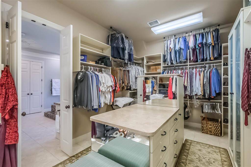 Wow! The large primary closet features plenty of hanging space, built-in cabinetry, shelving and a wardrobe island.