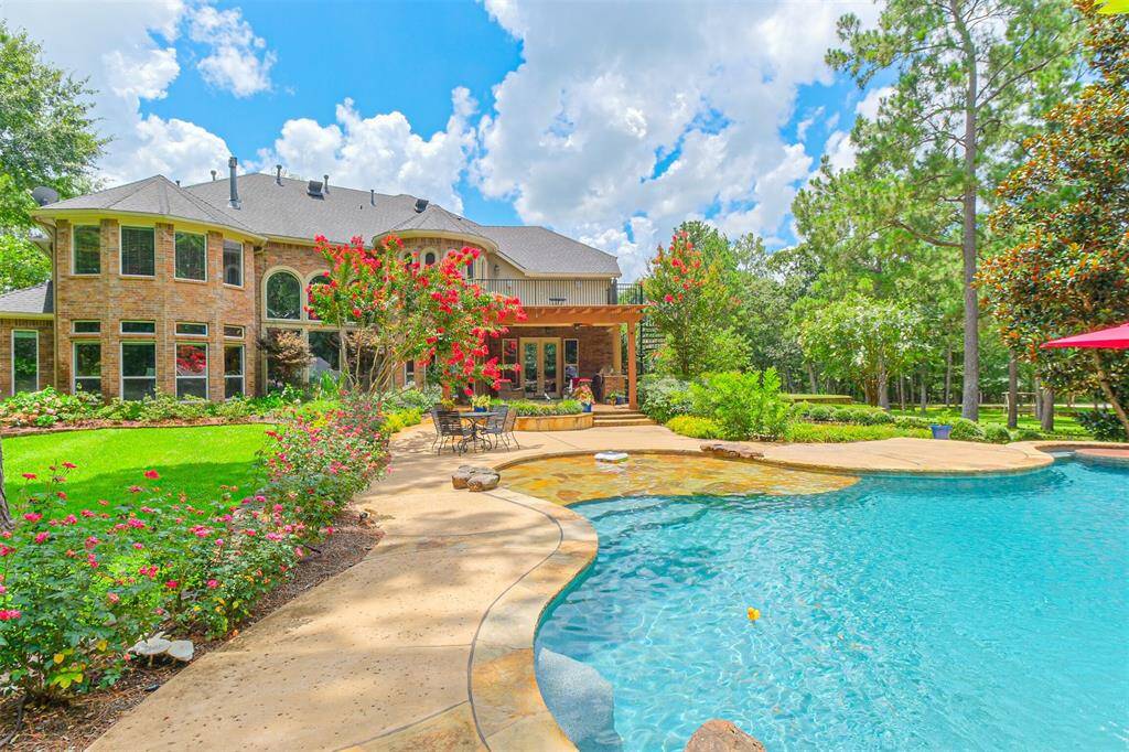 View of the expansive pool tanning ledge and covered dining area and open air balcony with spiral stairs.