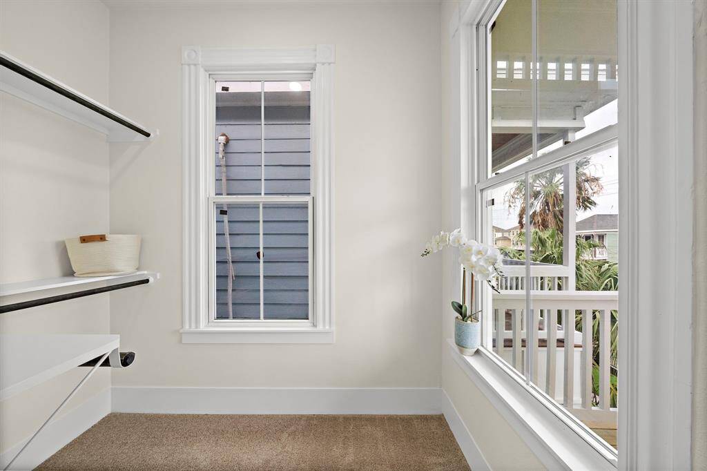 This cozy nook or walk-in closet features built-in shelving and a window that offers a view of the outdoor balcony and surrounding neighbors.