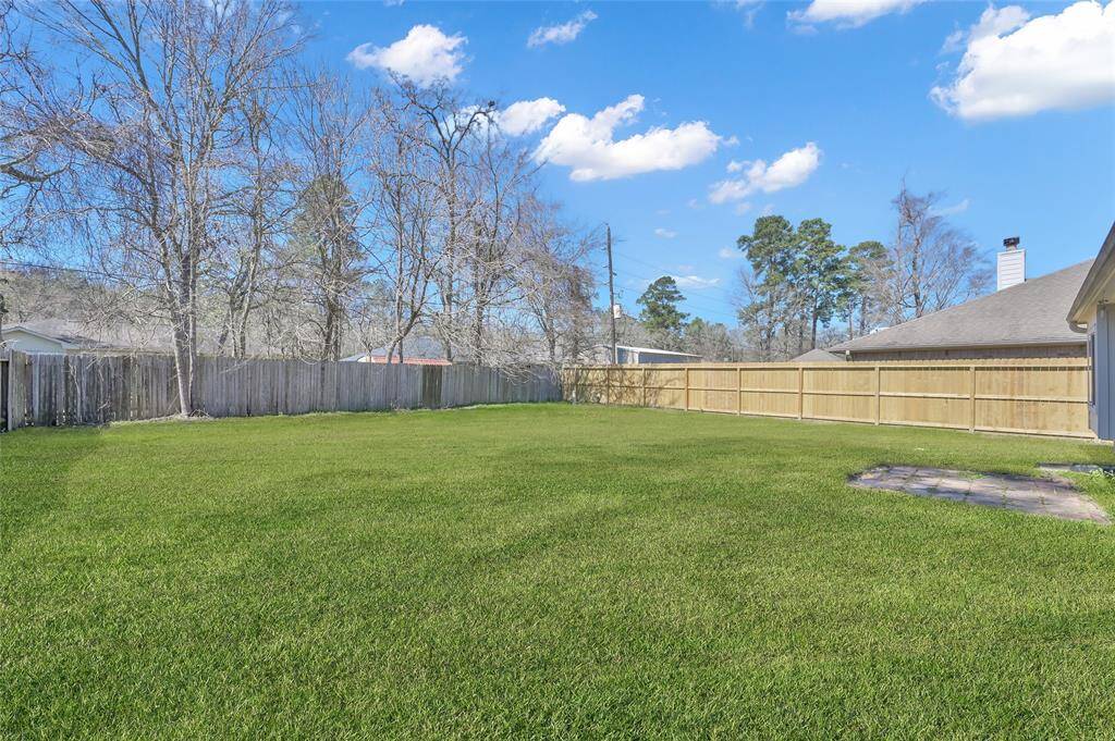 Spacious backyard with lush green lawn, bordered by wooden fencing for privacy. Ideal for outdoor activities and entertaining.