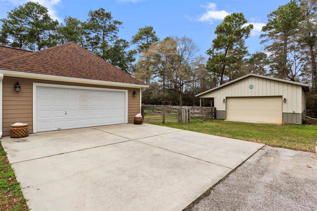 driveway leading to a double garage with a separate detached workshop or additional garage. The property is surrounded by trees, offering a sense of privacy and nature. Ideal for those needing extra storage or workspace.