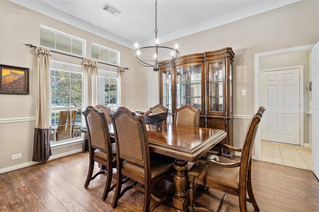 The Dining Room, located directly off the Kitchen, boasts high-end laminate flooring, crown molding, and chair rail detailing. A pair of windows, with transoms above, overlook the picturesque and spacious Front Yard.