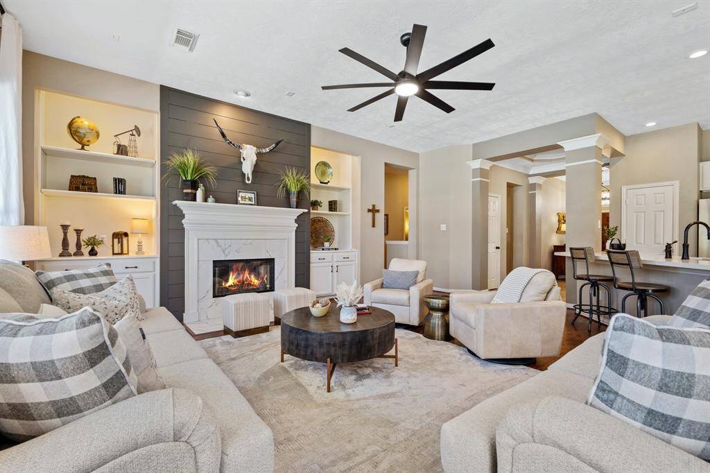 The marble-inspired, tile fireplace is a real showstopper thanks to the floor-to-ceiling, shiplap accent wall adorned in a striking black. A pair of well-lit built-ins flank either side of the gas fireplace, providing the perfect place to store games, pictures, and family mementos.