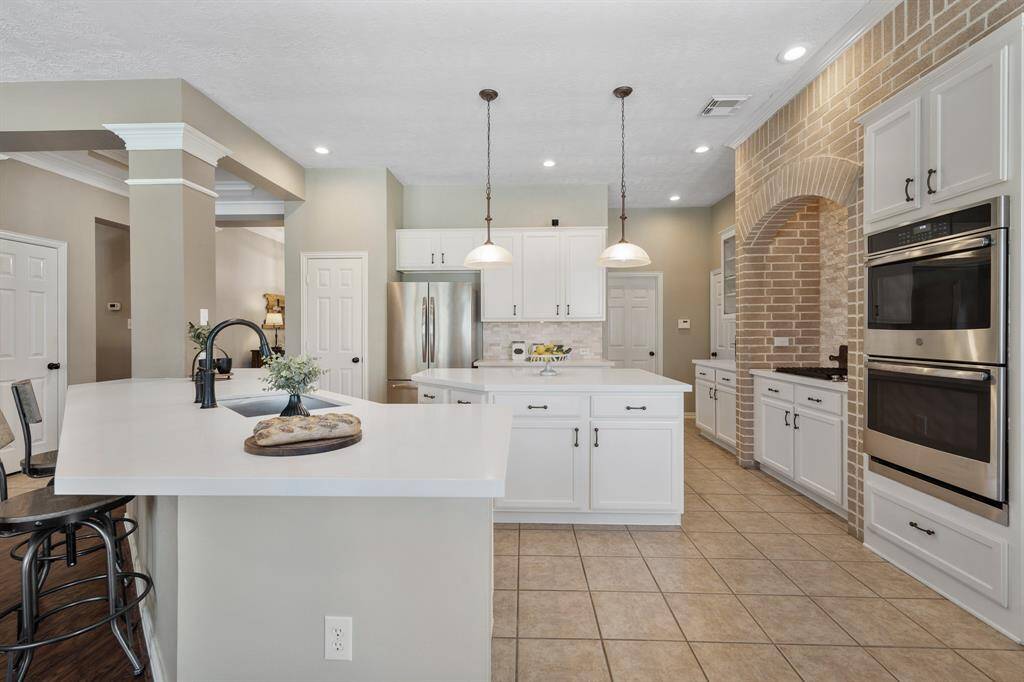 The Kitchen is light and bright thanks to the clean white cabinets with white quartz countertops above. A stacked stone backsplash perfectly marries the whites and tans found throughout the space.