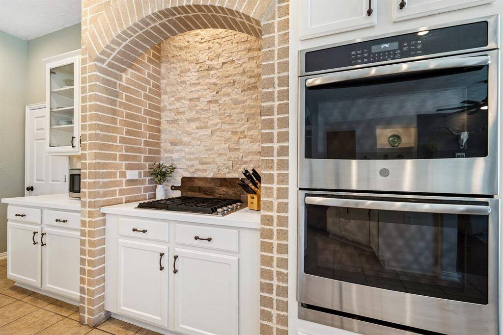 The home boasts a GE appliance package that includes built-in, dual ovens, a 4-burner gas range, and whisper quiet dishwasher. The brick archway catches the eye and adds dramatic elegance to the space.