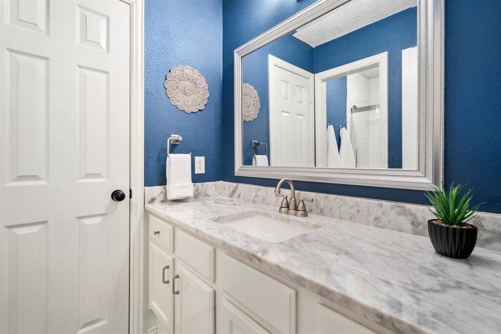 Both Secondary Bedrooms share this newly updated Bathroom. The space comes equipped with an extended vanity, undermount sink, quartz countertop, and framed mirror. The door straight ahead leads to a linen closet – an ideal place to store extra towels and toiletries.