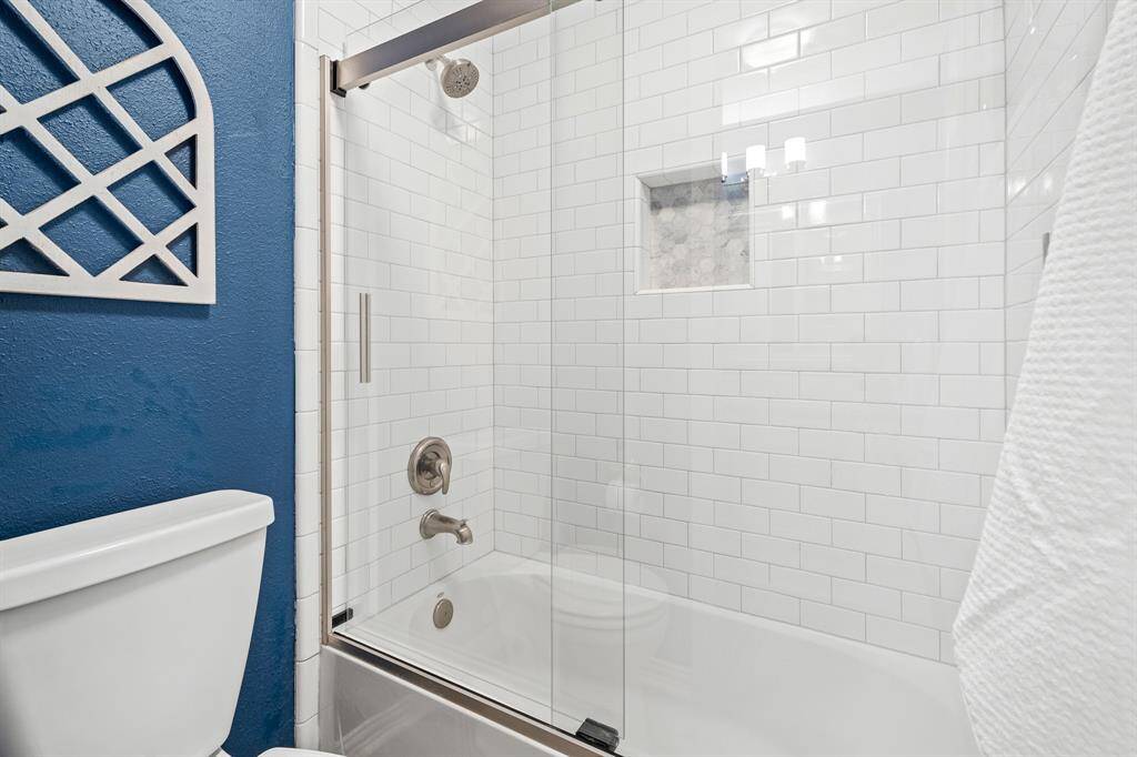 The Secondary Bathroom boasts this shower/tub combo with white subway tile that washes all the way to the ceiling. A decorative, honeycomb tile niche adds a decorative touch and brings in colors that coordinate with the blue hued walls.
