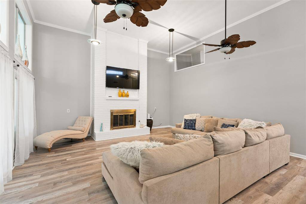 Living room features high ceilings and floor to ceiling brick fire place.