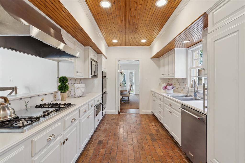 The well-equipped kitchen [16' x 9'] features reclaimed brick floors* from New Orleans. The wood paneled ceiling of bead boarding adds texture to the space. There is a traditional swinging door, outfitted with brass hardware. This door can be left open or be used to close off the kitchen alltogether.