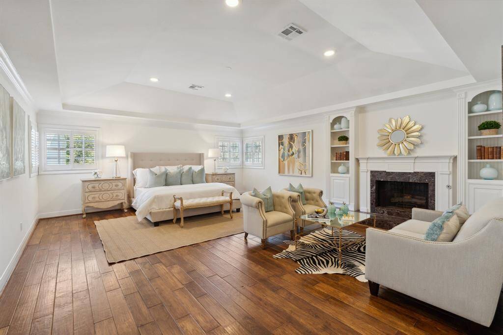 The beautiful primary bedroom [21' x 17'] boasts a vaulted, 14-foot ceiling, engineered hardwood flooring [2006*], two sets of corner windows, mirror-image arched shelving units, plus a deluxe lounging area adjacent to the fireplace.