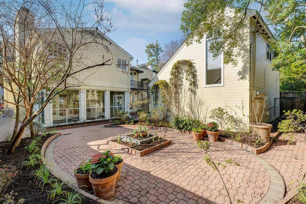 The backyard is reminiscent of a New Orleans courtyard setting with its interlocking pavers. The two arched trellies on the exteror garage wall are blooming with yellow jasmine. The  red tulips have just sprouted from the center flower bed. In the backyard, you will find azaleas, liriope, lantana, specimen trees and shrubs. From this vantage point, you can appreciate the wonderful size of the side yard.
