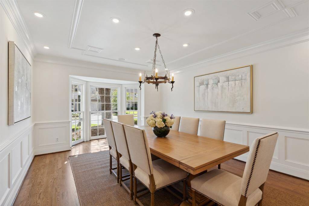 The dining room [18' x 13'] exudes simple elegance. Special features include the beautiful, big bay window, symmetrical block paneling, tray ceiling detail, newly* installed LED ceiling lights, and newly* refinished hardwood floors-February 2025. *Per Seller