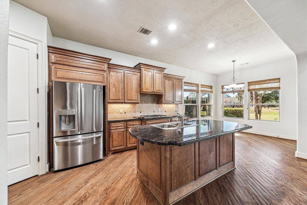 Modern kitchen boasts stainless steel refrigerator, a spacious walk-in pantry, under cabinet lighting and ample counterspace and storage.
