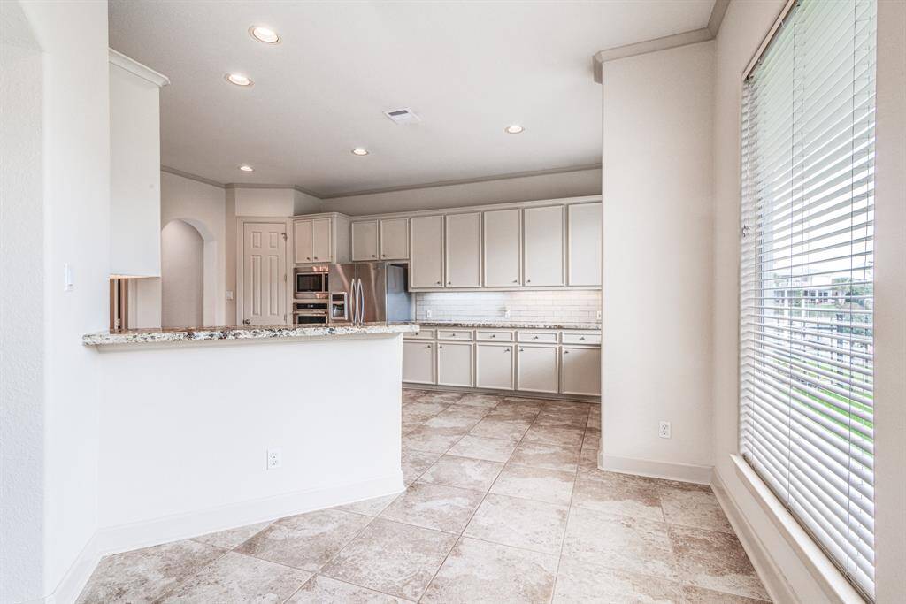 View of the beautiful marina from the breakfast bar area. Continuous tile flooring, recessed lighting, crown molding, high ceilings and neutral decor throughout this entire home. It's move in ready & Stunning!