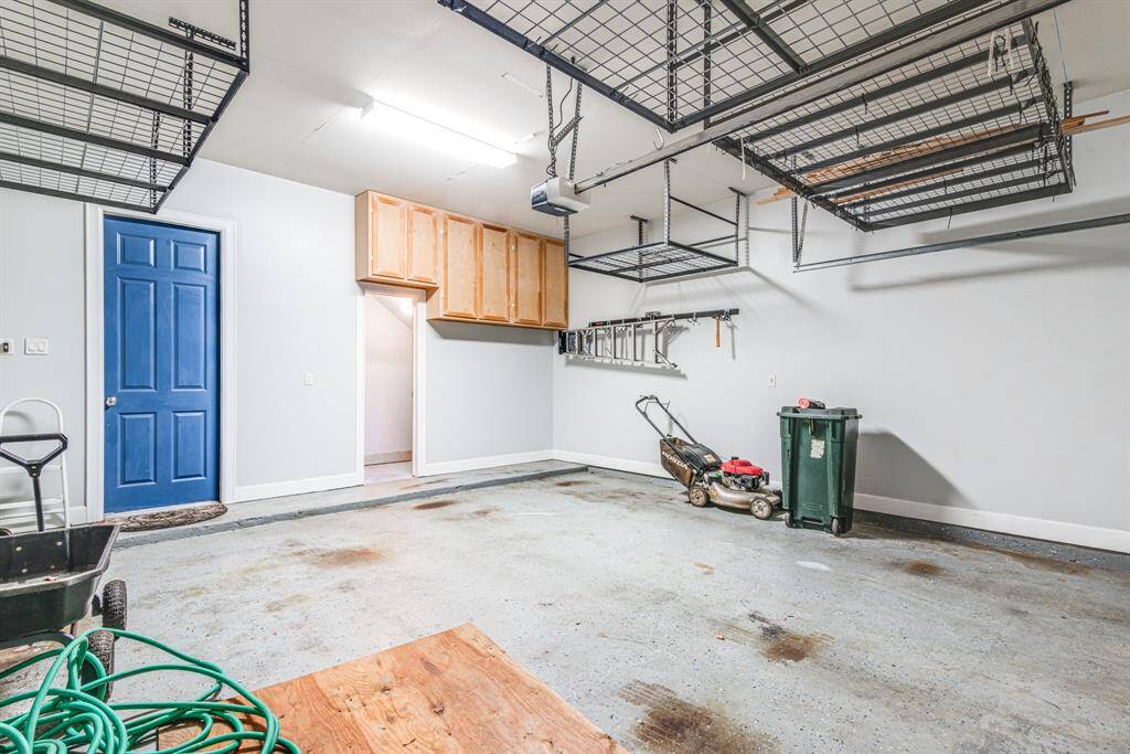 Two car garage has additional storage room, cabinetry and extra storage racks for various water toys and decorations.