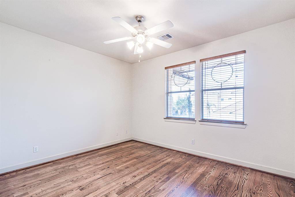 Upper level bedroom with ceiling fan and quality wood flooring.