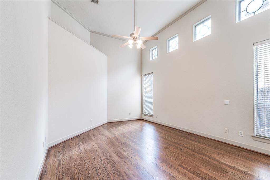 Primary bedroom on main level with 14' ceiling with fan and windows overlooking side yard.