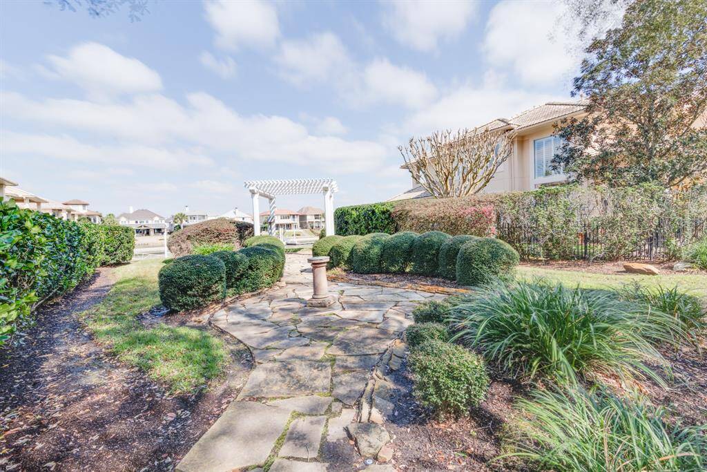 Open space behind rear of home with walkway, pergola and waterfront green space.