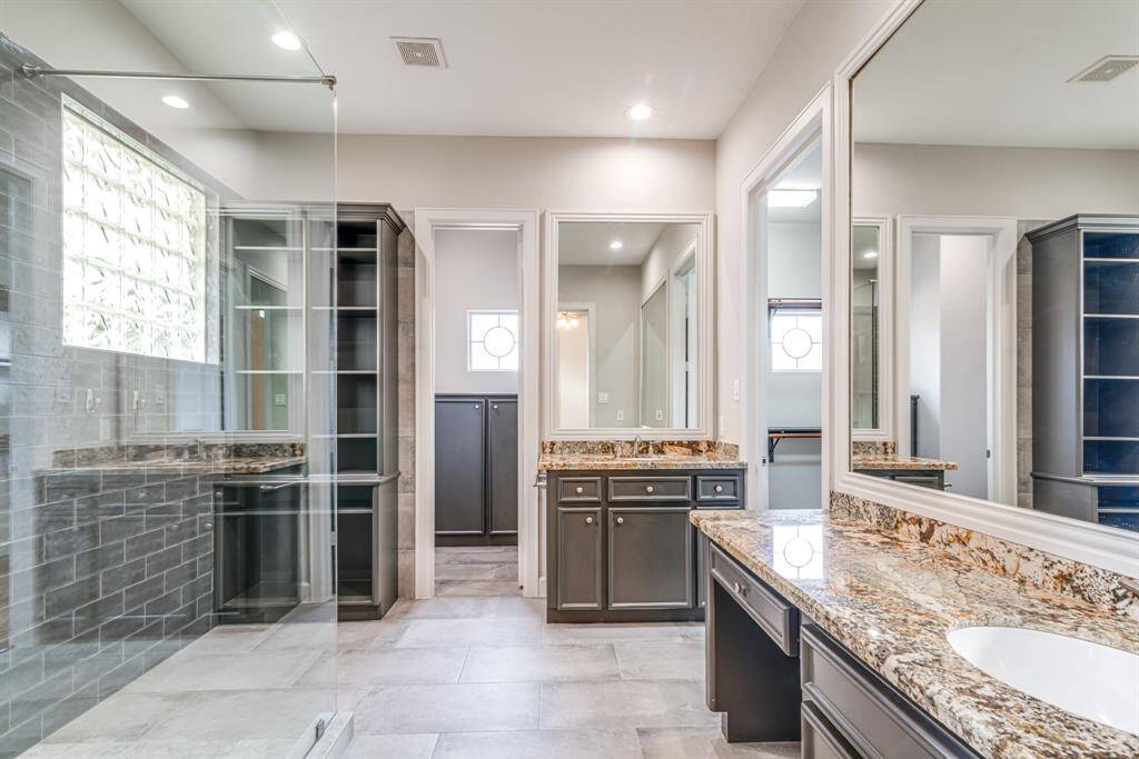 Primary en suite is updated with granite counter tops, two vanities, and gorgeous custom shower.