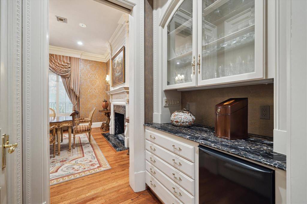 Kitchen with oak hardwood floors, recessed lighting, custom millwork, solid surface countertops, ceramic tile backsplash, dual solid surface sinks, brass plumbing fixtures, abundant front glass cabinetry, under cabinet lighting, brass hardware, Palladian window, island with a breakfast bar,