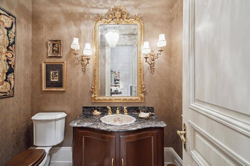 Laundry room with ceramic tiles floors in a brick pattern, florescent lighting, custom millwork, oculus window, solid surface countertops, ceramic sink, brass plumbing fixtures, built-in ironing station, orkspace with desk area, and broom closet. Built-in cabinetryBrass hardware